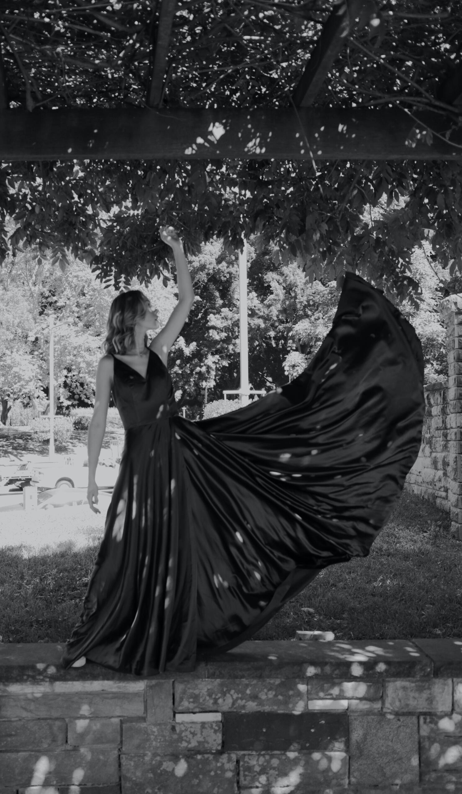 woman in long black dress standing underneath a tree